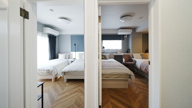 Ett hotellrum med två sängar, ett skrivbord, en stol och ett badrum som syns genom en öppen dörr.