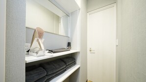 Ett badrum med en spegel, en handduksställning och en hylla med toalettartiklar.