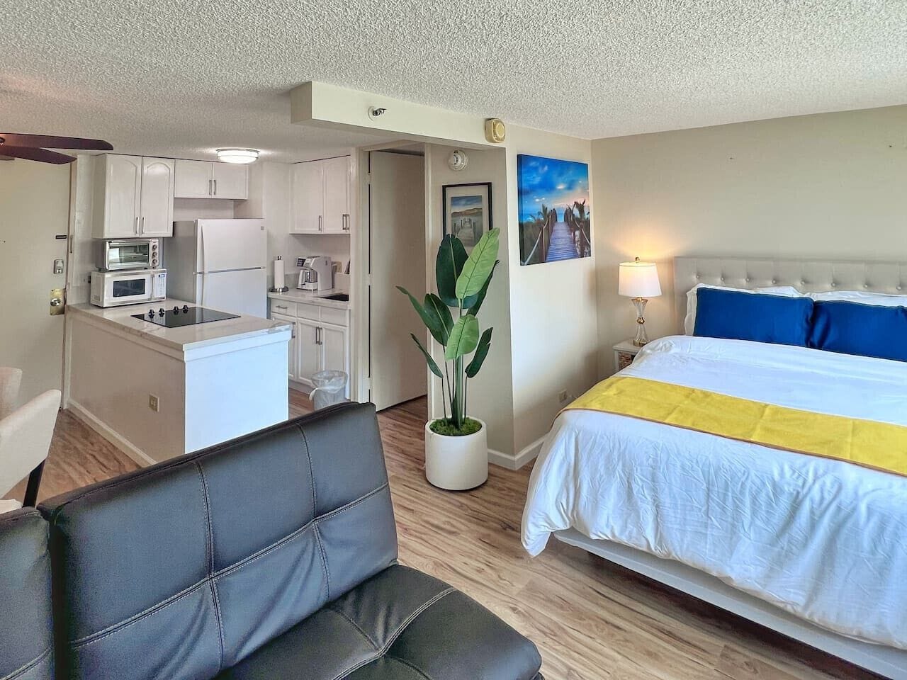 A hotel room with a bed, a small kitchenette, a dining area, and a living space.