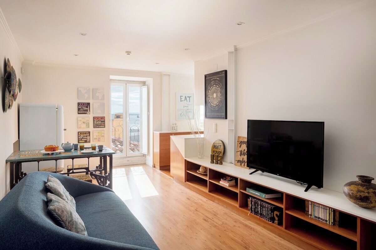 A modern living room with a sofa, TV, wooden shelves, and a dining area with a table and chairs.