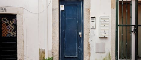 A building with a blue door, a number 22 sign above it, and a small window with a metal grill.