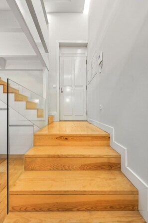 A staircase leading to a white door, with a glass railing on the left and a light-colored wall on the right. - Recanto do Porto with Private Patio and AC (Porto)
