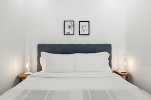 A neatly made bed with white linens, a dark headboard, and two bedside lamps. - Recanto do Porto with Private Patio and AC (Porto)