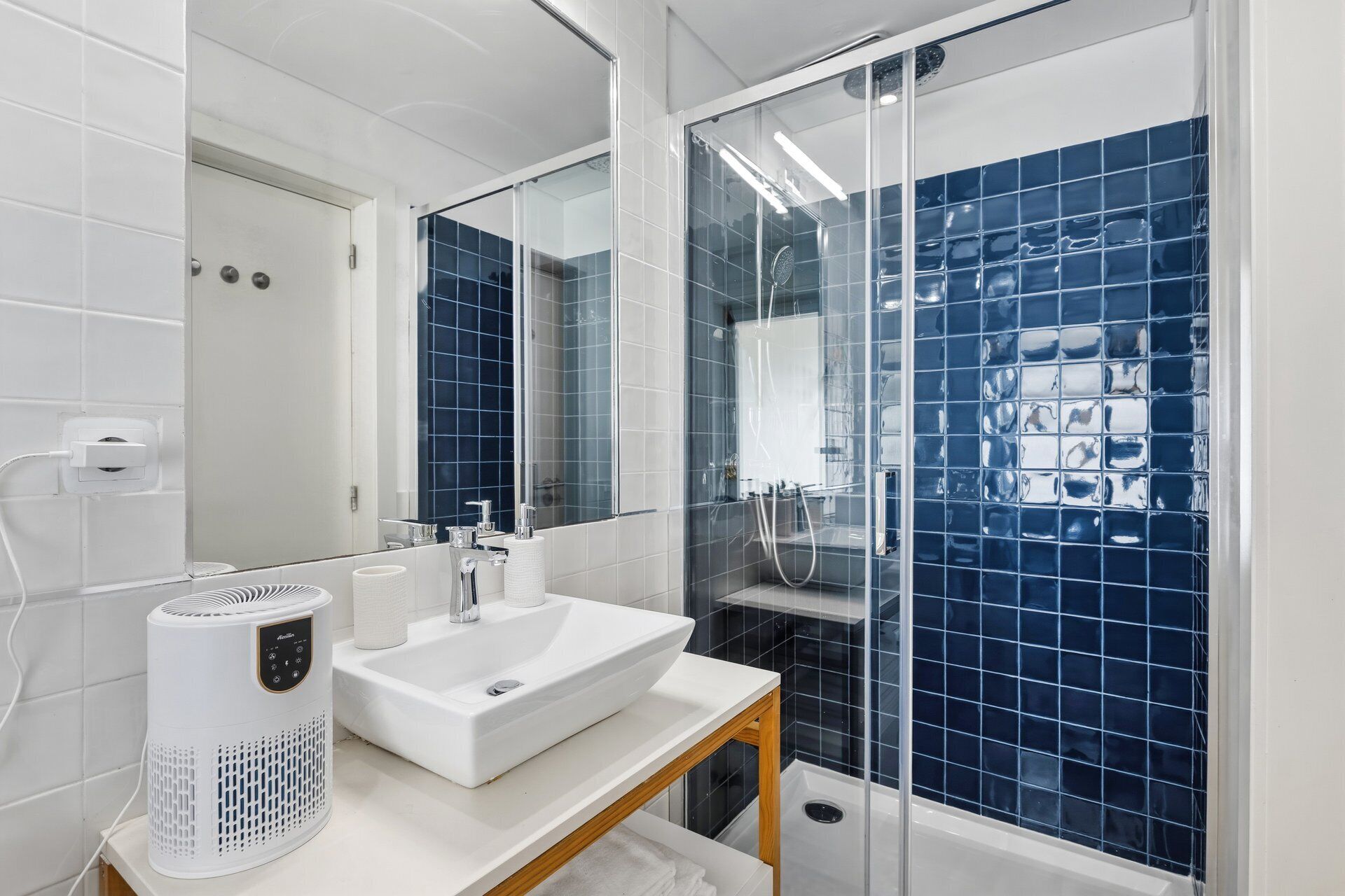 A modern bathroom with a white sink, a handheld showerhead, and a glass-enclosed shower.