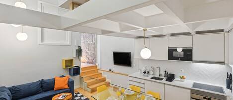 Un apartamento moderno con sala de estar, comedor, cocina y una escalera.