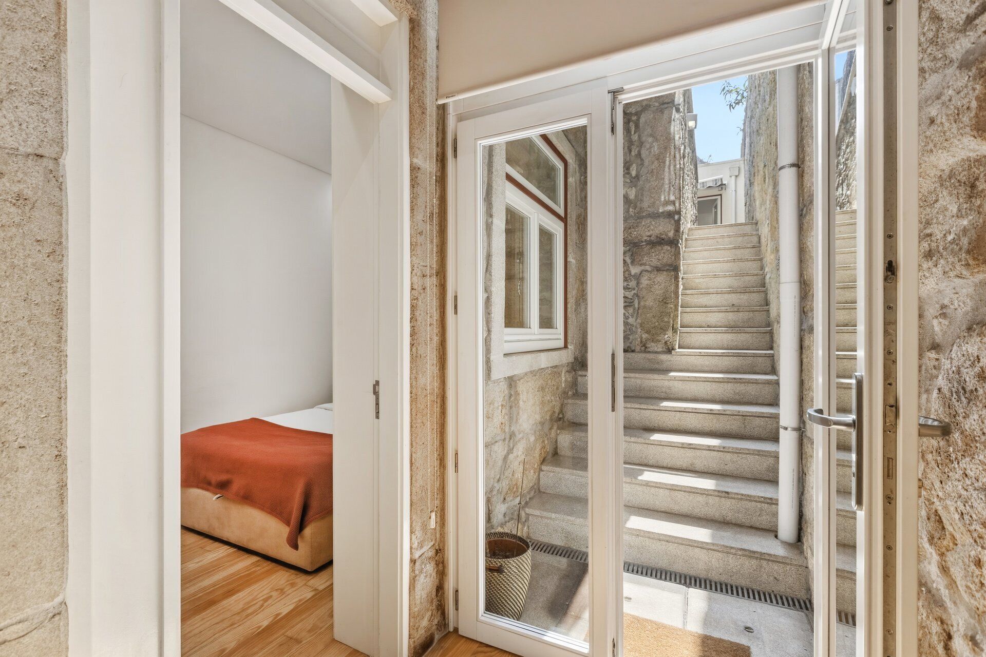 A room with a bed, a sliding glass door leading to a stone staircase.