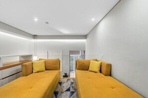 A modern, minimalist room with two yellow sofas, a wooden bench, and a geometric patterned rug. - Recanto do Porto with Private Patio and AC (Porto)