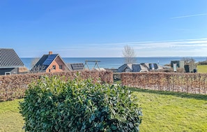 Una zona residencial costera con casas, cielo despejado y el mar al fondo.
