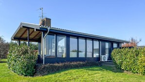 Uma casa moderna com uma grande janela de vidro, chaminé e varanda coberta.
