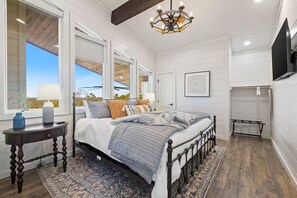 A bedroom with a bed, a bedside table, a rug, a chandelier, and a window. - Views, Pickleball, Hottub, Gameroom, EV, Multi-Fam (Broken Bow)