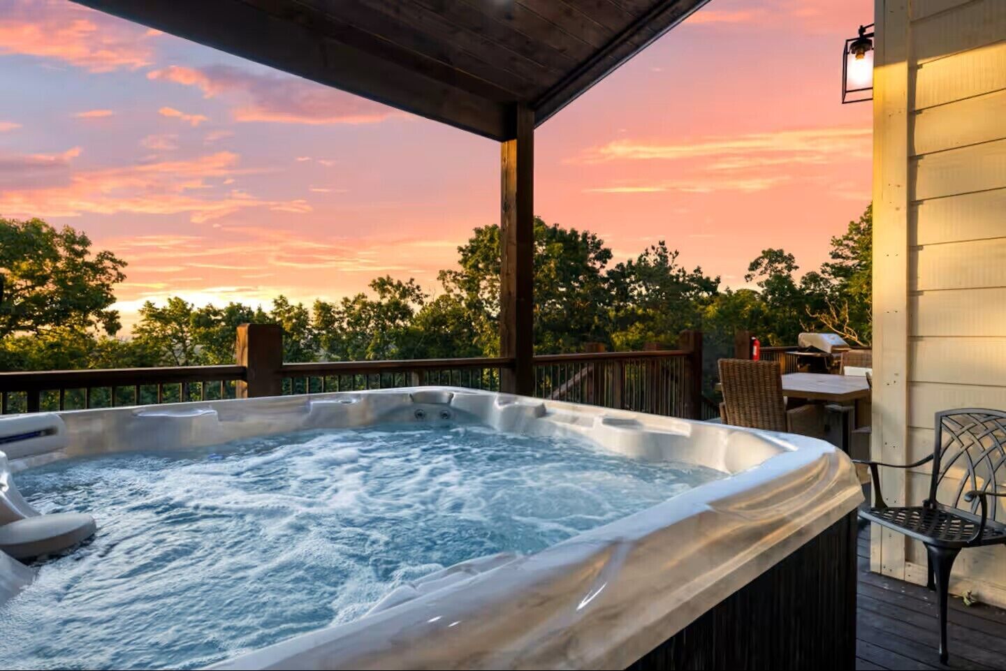 Een hottub op een houten terras met uitzicht op de ondergaande zon.