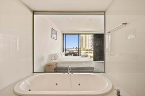 Un bagno moderno con una vasca da bagno ampia, un letto con vista e una grande finestra.
