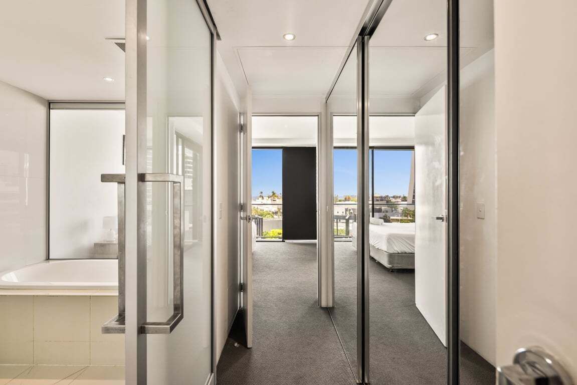 Ein modernes Hotelzimmer mit Glastür und Balkon, der einen Blick auf die Stadt bietet.