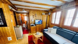 Ein Holzinnenraum mit einer Couch, einem Fernseher und einem kleinen Tisch.