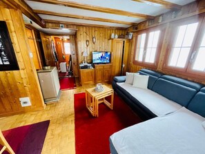 A wooden interior with a sofa, television, and a small table.