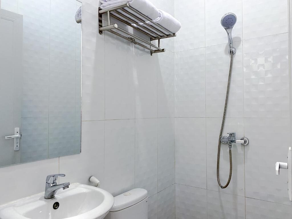 Kylpyhuone, jossa on pesuallas, wc, suihku ja pyyheteline.
