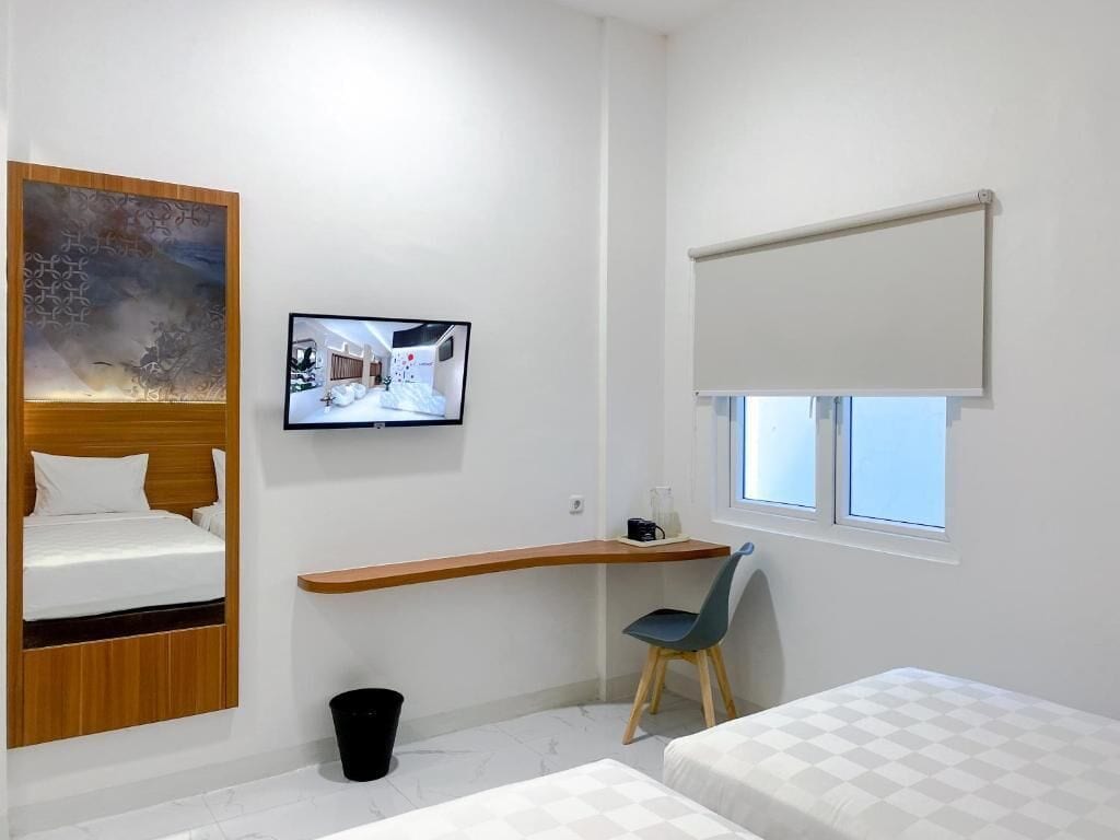 Ein modernes Hotelzimmer mit Bett, Schreibtisch, Stuhl, Fernseher und Fenster.