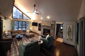 Ein Wohnzimmer mit Kamin, einer Sofagarnitur und einem großen Fenster.