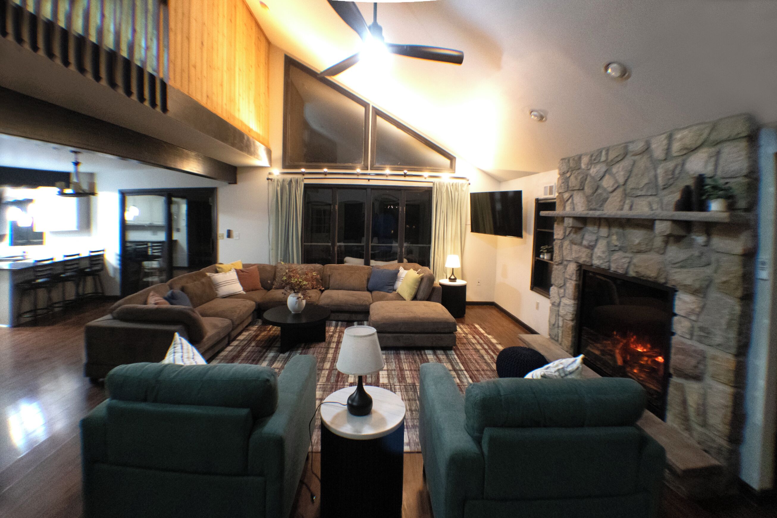 A spacious living room with a large sectional sofa, a fireplace, and a dining area in the background.