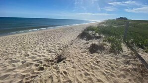 Ein Sandstrand mit klarem Himmel und Meer.