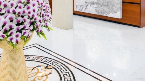 A hotel reception area with a marble reception desk, a large floral arrangement, and a television mounted on the wall. - Tien Thanh Hotel (Hung Nguyen)