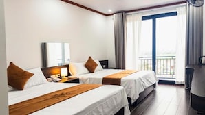 A hotel room with two beds, a desk, a chair, and a large window with curtains. - Tien Thanh Hotel (Hung Nguyen)