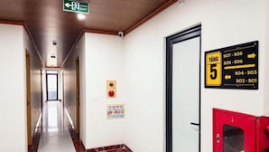 A hotel corridor with an exit sign, a fire alarm, and a directory sign indicating room numbers. - Tien Thanh Hotel (Hung Nguyen)