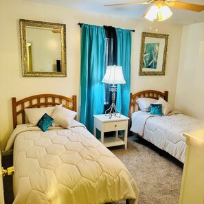 A bedroom with two beds, a nightstand, a lamp, and a ceiling fan. - Cozy Condo 2 - Adorable 3-bedroom townhome with AC in niceville (Niceville)