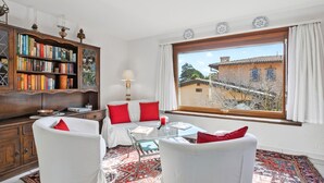 A room with a large window, a bookshelf, a sofa, and a glass table. - Casa Viola Losone for 8, Losone, Switzerland (Losone)