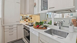 A modern kitchen with white cabinetry, a stainless steel sink, and a window above the countertop. - Casa Viola Losone for 8, Losone, Switzerland (Losone)