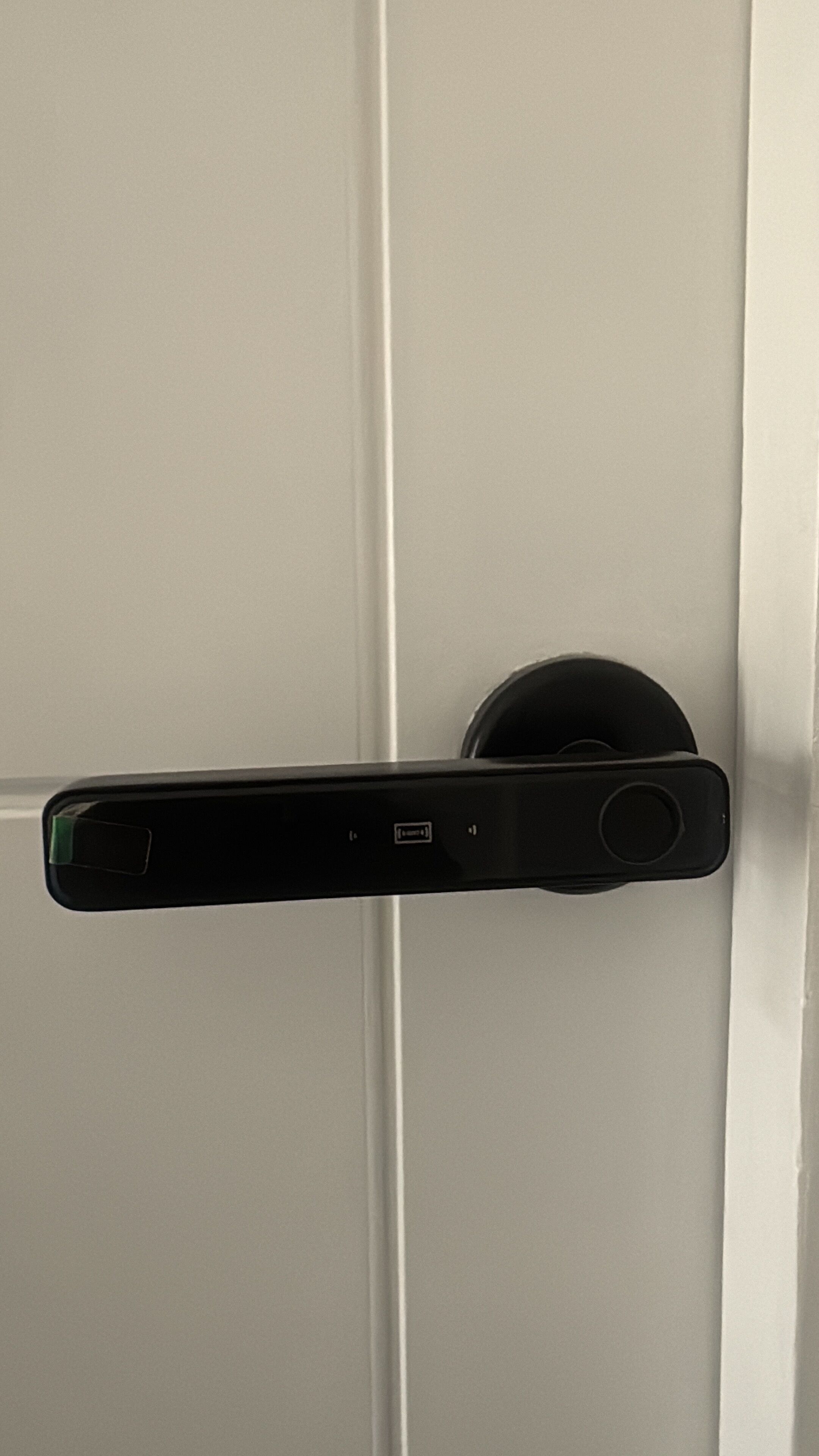 Una puerta con un dispositivo electrónico negro montado, probablemente un sistema de seguridad o control de acceso.