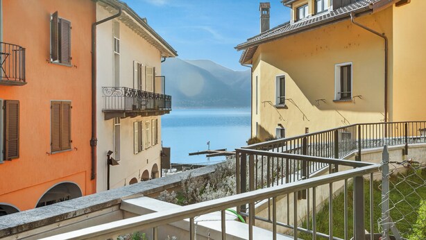 Un bâtiment situé sur la côte, doté de balcons, offrant une vue dégagée sur la mer et ayant une montagne en arrière-plan.