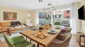 Un salon moderne comprenant un coin repas, un canapé, une table basse et un tableau au mur.