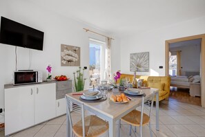 A modern kitchen with a dining area, a flat-screen TV, and a sofa. - Agritur Laura- Oasi di luce 5 with Shared Garden, Torbole sul Garda, Italy (Torbole sul Garda)
