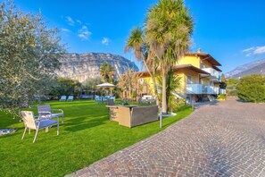 A hotel with a patio area, outdoor seating, and a mountain view. - Agritur Laura- Oasi di luce 5 with Shared Garden, Torbole sul Garda, Italy (Torbole sul Garda)