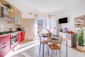 Une cuisine moderne avec un coin repas, un téléviseur fixé au mur et une vue sur l’extérieur.
