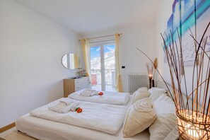 A bedroom with a bed, a bedside table, a mirror, a window with curtains, and a wall with artwork. - Agritur Laura- Oasi di luce 5 with Shared Garden, Torbole sul Garda, Italy (Torbole sul Garda)