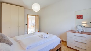 Une chambre à coucher comprenant un lit, une armoire, une commode et un luminaire suspendu.