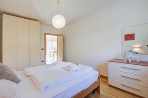 A bedroom with a bed, a wardrobe, a dresser, and a hanging light fixture. - Agritur Laura- Essenza di rosa 2 with Shared Garden, Torbole sul Garda, Italy (Torbole sul Garda)