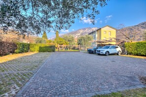 Ein gepflasterter Weg führt zu einem Eingang mit einem Tor, darin ist ein Auto geparkt.