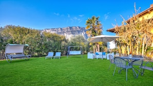 Un jardin bien entretenu, avec une pelouse verdoyante, du mobilier d’extérieur et une vue sur une chaîne de montagnes.