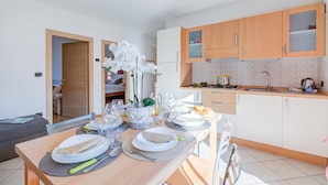 Une cuisine moderne avec des meubles en bois, une table à manger pour deux personnes et un petit coin repas agrémenté d’un canapé.