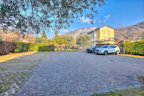 A paved driveway leading to a gated entrance with a car parked inside. - Agritur Laura - Danza di colori 3 with Shared Garden, Torbole sul Garda, Italy (Torbole sul Garda)