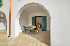 An interior courtyard with a dining table, chairs, and an archway.