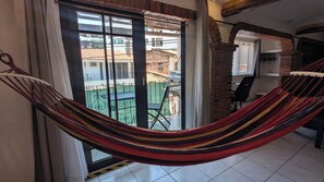 Eine Hängematte in einem Zimmer mit Blick auf einen Balkon und eine Backsteinmauer.