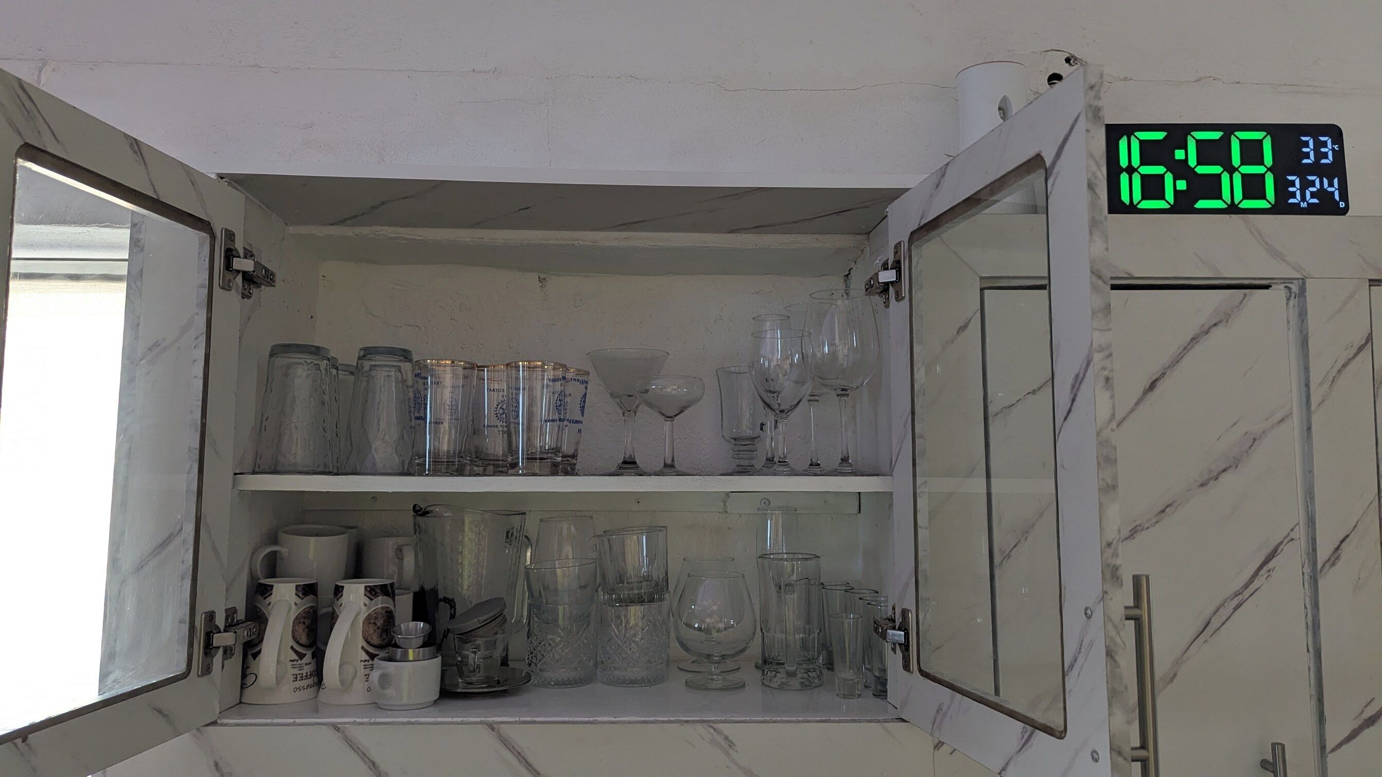 A storage cabinet with shelves containing various glassware and mugs.