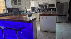 A modern kitchen with marble countertops, a built-in stove, and a refrigerator. - MADERO A" HOUSE. ZONA ROMANTICA PV. A SPACIOUS, COZY, CENTRALLY LOCATED APARTMENT (Puerto Vallarta)
