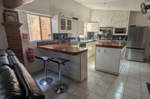 A modern kitchen with a central island, white cabinets, and a stainless steel refrigerator. - MADERO A" HOUSE. ZONA ROMANTICA PV. A SPACIOUS, COZY, CENTRALLY LOCATED APARTMENT (Puerto Vallarta)