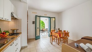 Una cocina compacta con estufa, armarios y un comedor con mesa y sillas.