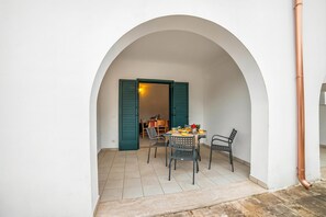 Un comedor con una mesa y sillas, un arco y un suelo de baldosas.